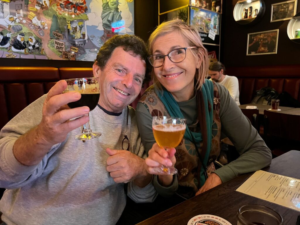 2 people enjoying a beer and smiling at camera