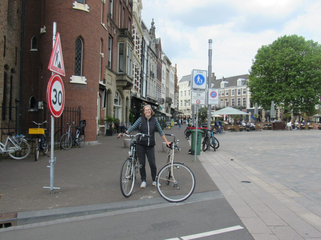 street scene I The Hague with woman standing holding 2 bicycles