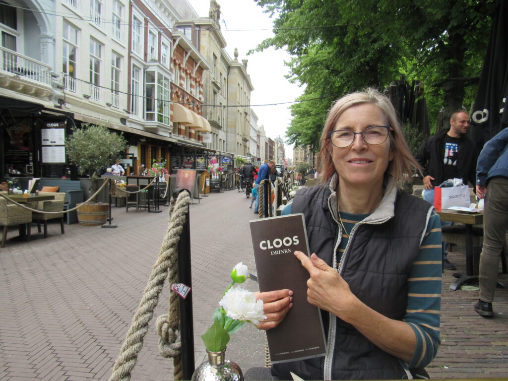 woman sitting at cafe on street, holding menu