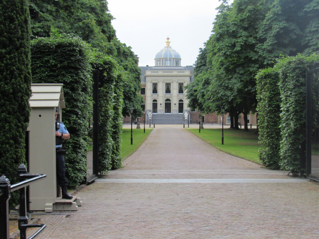 Grand building at end of tree lined driveway. Residence of Dutch king.