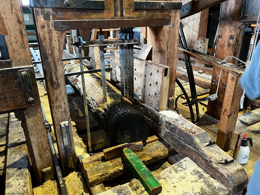 Inside dutch sawmill showing log being cut by blades